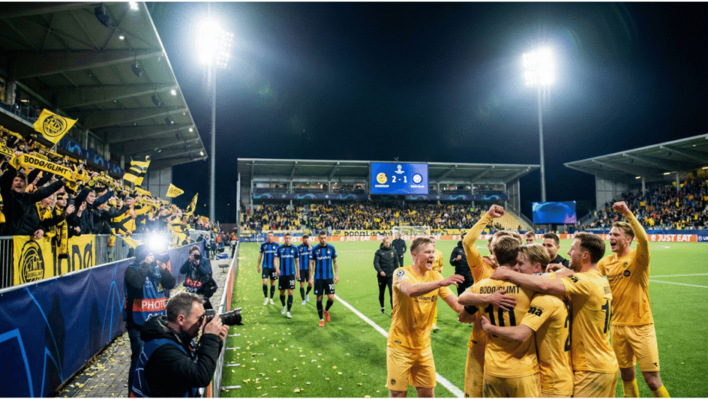 Bodø/Glimt players in yellow celebrate a goal against Inter Milan on the pitch, while Inter players in blue and black look dejected in the background.
